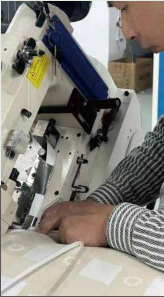 Worker sewing the quilted border tape on a hand-built mattress